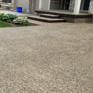Exposed aggregate concrete home entrance stairs and side walkway with floral garden.