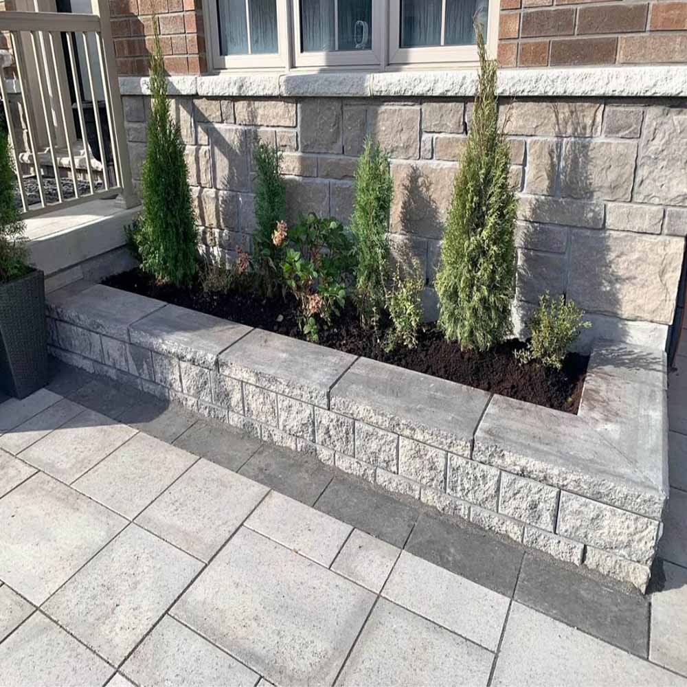 Custom stone retaining wall integrated with a tiered flower bed.