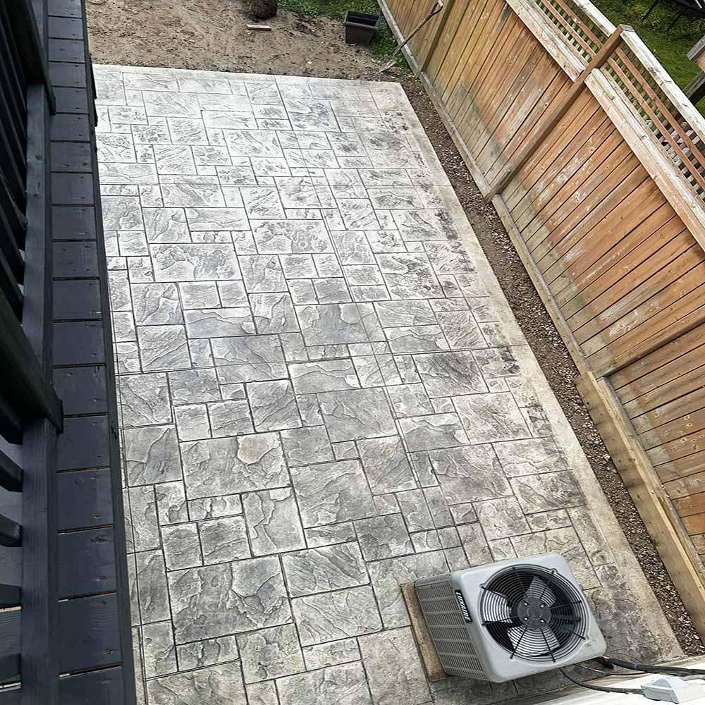 Grey-toned stamped concrete patio area without border.